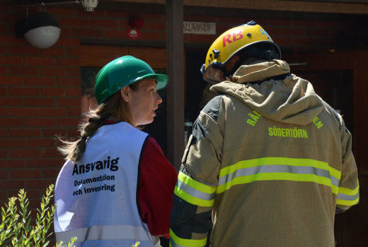 Nina Kjølsen Jernæs fra NIKU i samtale med brannvesenet under øvelse på redningsarbeid i kirke. Foto: Brannskyddsföreningen