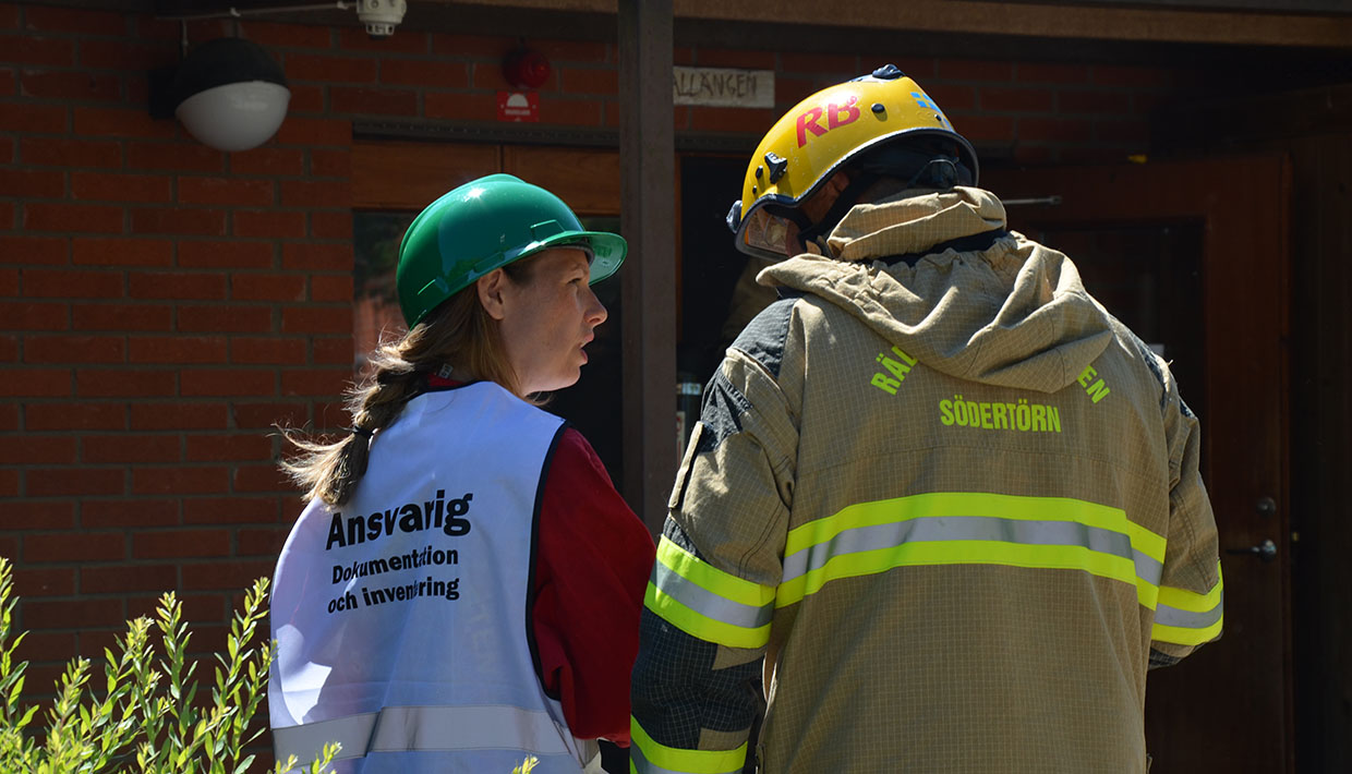 Nina Kjølsen Jernæs fra NIKU i samtale med brannvesenet under øvelse på redningsarbeid i kirke. Foto: Brannskyddsföreningen