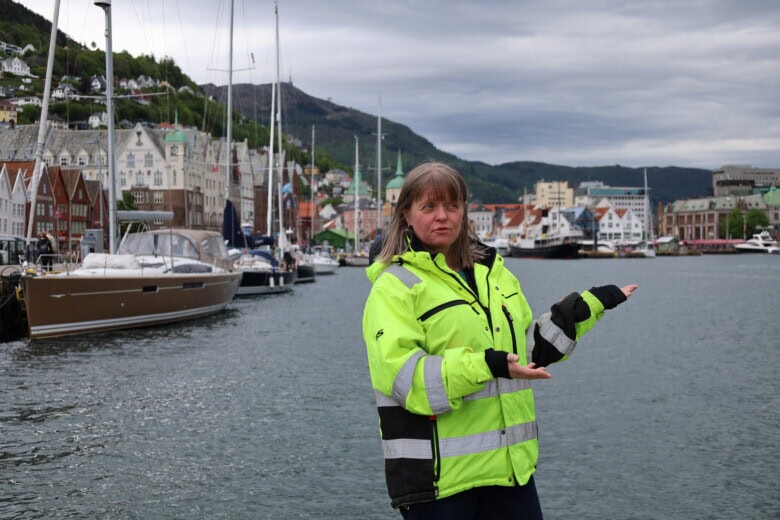 Bildet viser arkeolog Ambjørg Reinsnos med Bryggen i Bergen i bakgrunnen.