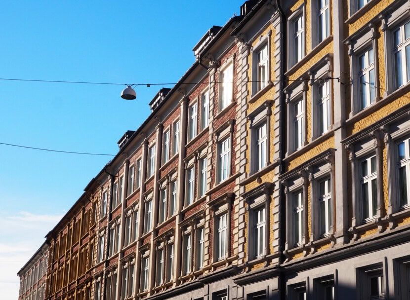 Fasaden på flere fargerike murgårder med blå himmel i bakgrunnen.